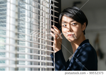 Woman looking through the blinds 99552373