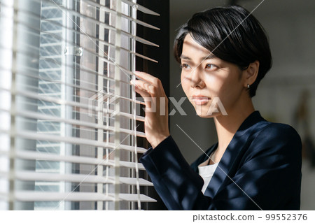 Woman looking through the blinds Woman looking through the blinds 99552376