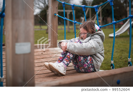 Upset problem child with head in hands sitting on playground alone concept for bullying, depression stress or frustration. School yard 99552604