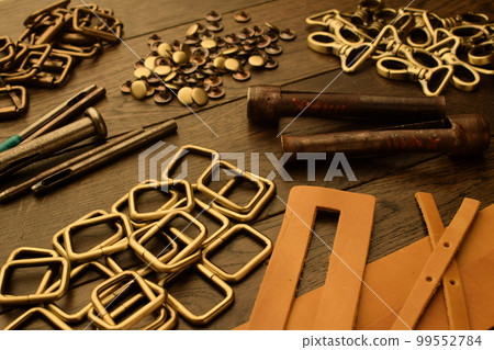 Metal hardware, leather pieces at handmade workshop, work tools Metal hardware, leather pieces at handmade workshop, work tools 99552784