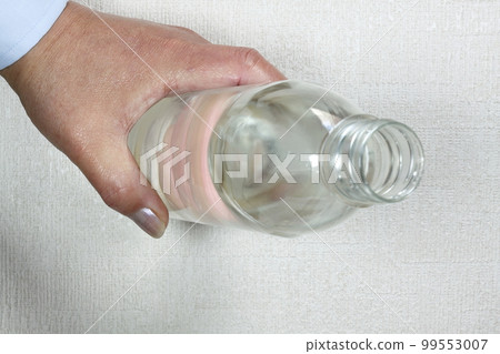 一個男人的手拿著一個裝有水的塑料瓶 99553007