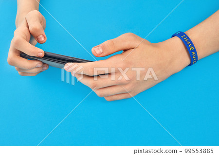 Autistic boy holding phone in two hands. Autism awareness. 99553885