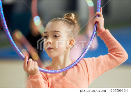 Gracefulness. Little girl, child, rhythmic gymnast training indoors, doing exercise with hoop. Concept of sport, childhood, rhythmic gymnastics Gracefulness. Little girl, child, rhythmic gymnast training indoors, doing exercise with hoop. Concept of sport, childhood, rhythmic gymnastics 99556664