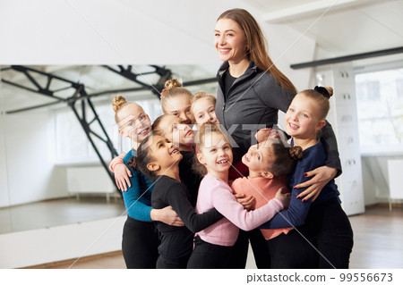 Happy smiling young woman, coach and little girls, kids indoors. Rhythmic gymnastics. Winners. Positivity. Concept of sport, childhood, rhythmic gymnastics Happy smiling young woman, coach and little girls, kids indoors. Rhythmic gymnastics. Winners. Positivity. Concept of sport, childhood, rhythmic gymnastics 99556673