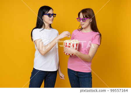 Two beautiful young women, sisters - twins on yellow background 99557164