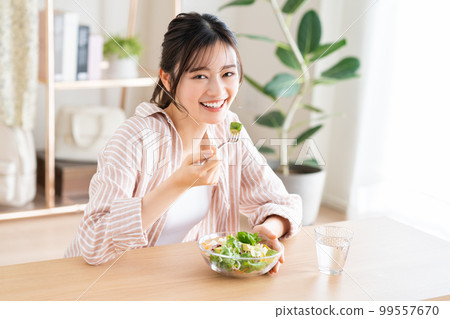 Young woman eating avocado salad 99557670