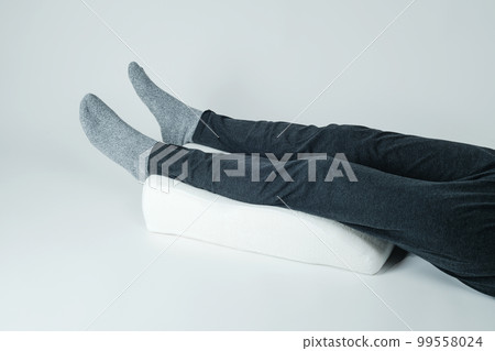 man using a leg elevation pillow 99558024