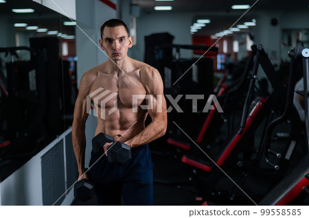 Shirtless man doing bicep exercises with dumbbells in the gym. Shirtless man doing bicep exercises with dumbbells in the gym. 99558585