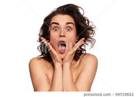 Shocked beautiful young woman with bare shoulders posing over white background. Fashion, beauty, spa, cosmetology, skincare concept Shocked beautiful young woman with bare shoulders posing over white background. Fashion, beauty, spa, cosmetology, skincare concept 99558682