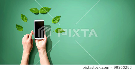 Person holding smartphone with green leaves 99560293