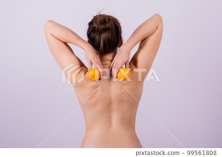 Slender athletic woman topless holds a tangerine in her hands. Cellulite. Healthy lifestyle Slender athletic woman topless holds a tangerine in her hands. Cellulite. Healthy lifestyle 99561808