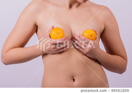 Slender athletic woman topless holds a tangerine in her hands. Cellulite. Healthy lifestyle 99561809