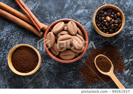 Concept of tasty snack for hot drink - cookies in the shape of coffee seeds Concept of tasty snack for hot drink - cookies in the shape of coffee seeds 99561937