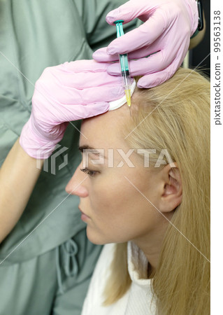Trichologist, beautician doing blond woman hair mesotherapy procedure. White doctor does scalp injections with syringe. Bio stimulation, hair cells treatment, hair loss,alopecia prevention. Vertical. 99563138