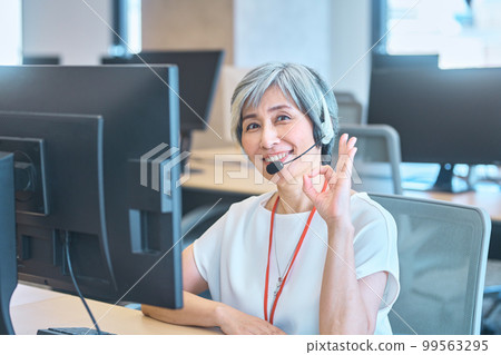 A veteran female operator wearing a headset in the office A veteran female operator wearing a headset in the office 99563295