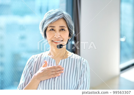 A veteran female operator wearing a headset in the office A veteran female operator wearing a headset in the office 99563307