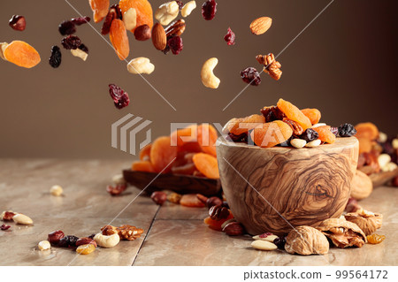 The mix of nuts and raisins in a wooden bowl. 99564172