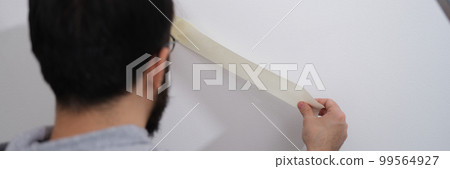 Home repair service master uses masking tape before painting 99564927