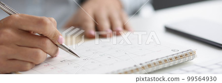 Closeup of person marking with pen and looking at date on calendar Closeup of person marking with pen and looking at date on calendar 99564930