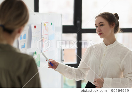 A woman in the office shows a report on the board A woman in the office shows a report on the board 99564959
