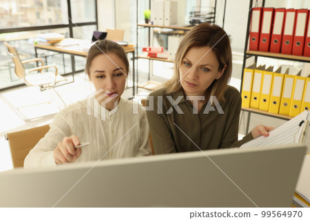 An employee in office teaches a woman computer literacy An employee in office teaches a woman computer literacy 99564970