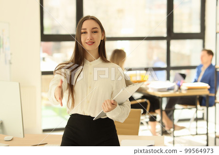 A beautiful woman in office holds out a hand for greeting 99564973