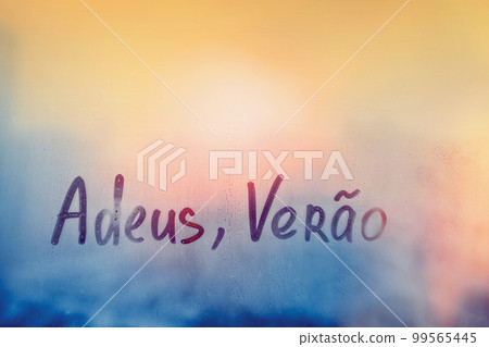 lettering Adeus Verao in Portuguese language is good bye summer in english on foggy glass on sunset window 99565445