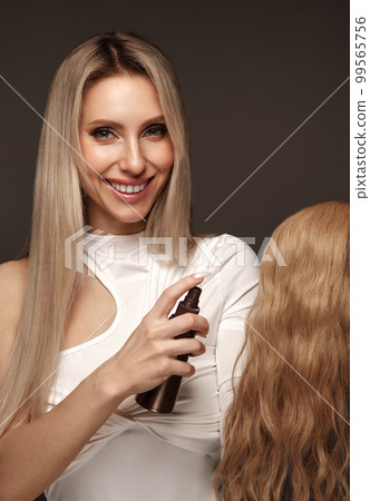 Beautiful blond girl with a perfectly hair, and classic make-up with a strand of hair for extension. Beauty face and hair. 99565756