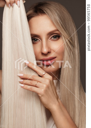 Beautiful blond girl with a perfectly hair, and classic make-up with a strand of hair for extension. Beauty face and hair. Beautiful blond girl with a perfectly hair, and classic make-up with a strand of hair for extension. Beauty face and hair. 99565758