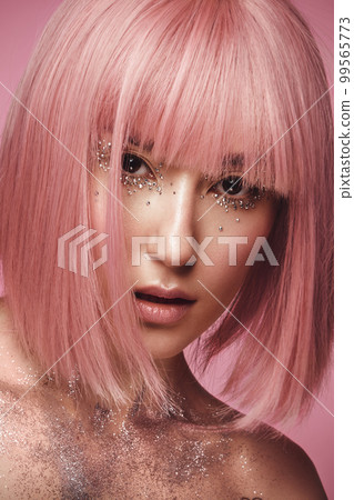 Beautiful woman in a pink wig and creative makeup with rhinestones. Beauty face. Beautiful woman in a pink wig and creative makeup with rhinestones. Beauty face. 99565773