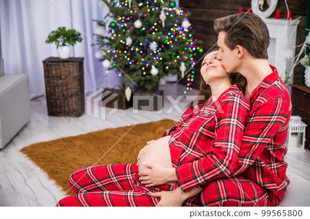 A man sits behind a woman leaning against him and kisses her on the cheek. A man sits behind a woman leaning against him and kisses her on the cheek. 99565800