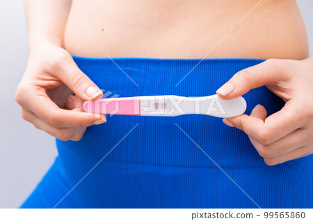 Close up woman holding a positive test near the belly. Close up woman holding a positive test near the belly. 99565860