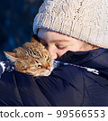 Smiling young girl holding her cat outdoors. 99566553