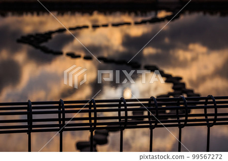 落日照亮的光亮的大海和人工池塘長廊 99567272