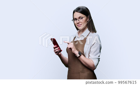 Young smiling woman in apron with smartphone, on white background Young smiling woman in apron with smartphone, on white background 99567615