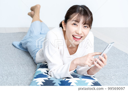 Woman who lays down and uses smartphone 99569097