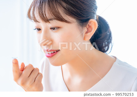 Women trying to wear contact lenses Women trying to wear contact lenses 99570253