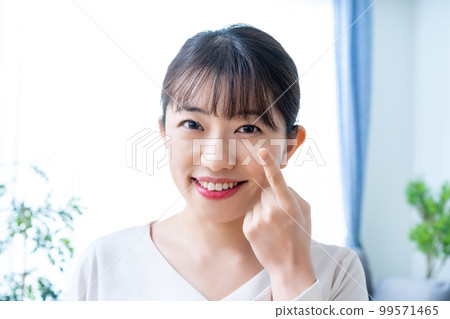 Women trying to wear contact lenses 99571465