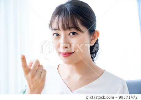 Women trying to wear contact lenses Women trying to wear contact lenses 99571472