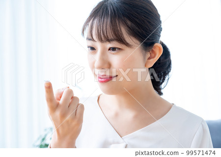 Women trying to wear contact lenses Women trying to wear contact lenses 99571474