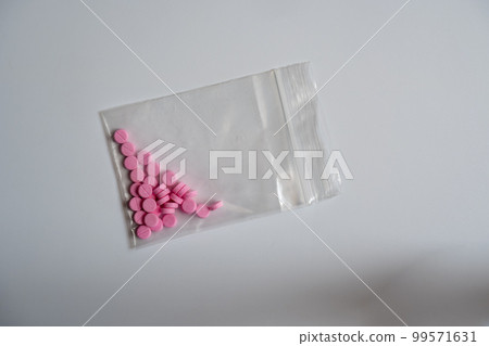 A small pink pill, contained in a zipped pouch A small pink pill, contained in a zipped pouch 99571631