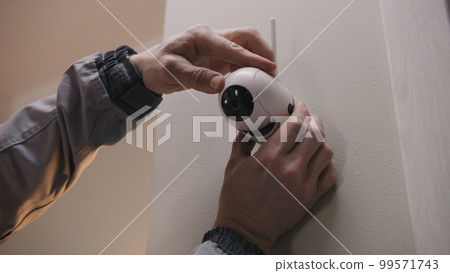 Installer puts security camera on wall mount 99571743
