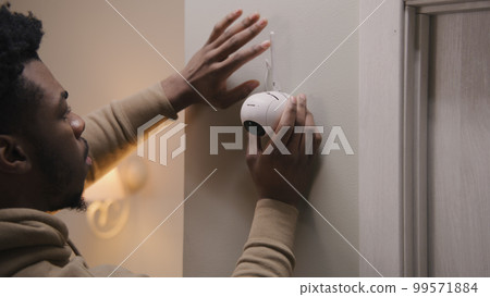 Man puts security camera on wall fastening 99571884