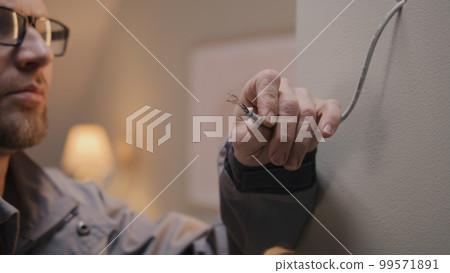 Electrician in uniform works with cable 99571891