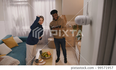 Multi ethnic couple set up security camera 99571957