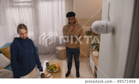 Multi ethnic couple set up security camera 99571998