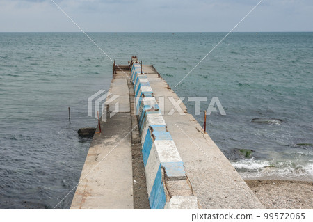 Stone pier on the emnankment of Feodosiain cloudy weather. Crimea Stone pier on the emnankment of Feodosiain cloudy weather. Crimea 99572065