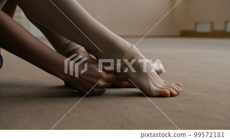 Ballerina takes off her pointe shoes 99572181