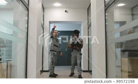 Men install CCTV cameras in office corridor 99572198