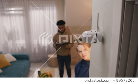 Multi ethnic couple set up security camera Multi ethnic couple set up security camera 99572203